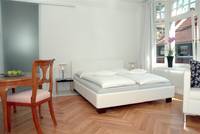 weißes Doppelbett am großen Fenster, schönes Holzparkett