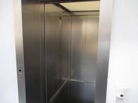 offenstehender Aufzug mit einer Metall-Innenkabine und Durchgangstür 