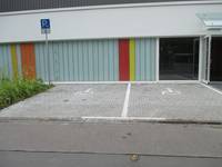 zwei Parkplätze,Bodenmarkierung mit dem Rollstuhlsymbol. Direkt vor Gebäude, links Schild 