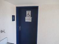 dunklere einflügelige Tür mit einem Hinweisschild mit Rollstuhlfahrer