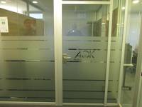 Glasfront mit Glastür. Auf Tür und Wand breite Streifen aus Milchglas. Auf einem Streifen ist das AOK-Logo