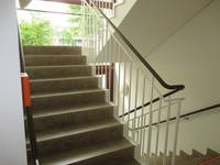 aufwärts und abwärts führende Treppe mit Handläufen, auf der Innenseite durchgehend. Nach der Treppe nach oben ist ein Podest und eine Glasfront