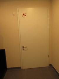 helle Tür vor einer hellen Wand, auf der Tür Rollstuhlsymbol
