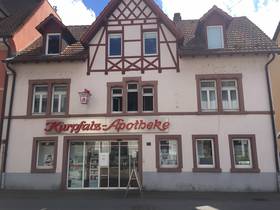 Historisches Gebäude mit hohem Giebel, im EG breite Schaufensterfront. Über dem Schaufenster ist der Schriftzug "Kurpfalz-Apotheke" angebracht