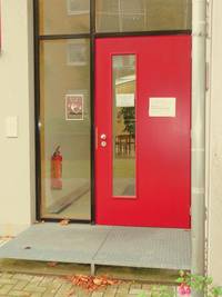 rote einflügelige Drehflügeltür mit Glaseinsatz und einer Außenstufe aus Metall