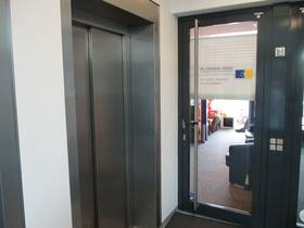 Eingang neben Aufzug, Glastür mit Streifen