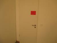 Eine weiße Tür in einer weißen Wand. Auf der Tür ist ein rotes Blatt mit der Aufschrift "Labor"