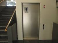 Ein Aufzug mit geschlossenen Türen aus Metall in einer weißen Wand