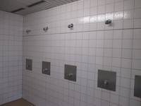 weiß gekachelter Raum mit vier Duschplätzen