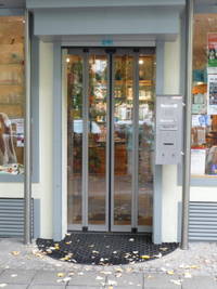 Automatische Glastüre, links vom Eingang Briefkasten und Gegensprechanlage mit Klingel