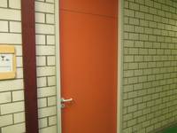 orangefarbene Tür, links davor Schild