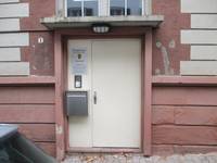 Eingang mit weißer einflügeligen Drehflügeltür, neben der Tür Briefkasten und Klingeln
