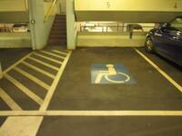 Ein Parkplatz mit einem blauen Behindertensymbol auf dem Boden. An der Wand ist die Zahl 5 angebracht