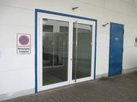  zweiflügelige Glastür mit blauem Rahmen und einer weißen Wand, links daneben Halteverbotsschild