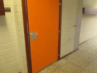 orangefarbige Türe mit braunem Rahmen in weißer Wand