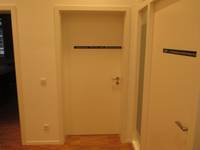 weiße Tür in weißer Wand, auf der Tür ist ein schmaler schwarzer Streifen mit Beschriftung, rechts ist eine weitere Tür