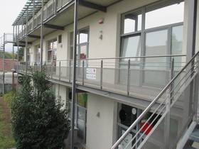 Mehrstöckiges Gebäude im Zentrum des Bildes ist ein Balkon der die Treppe rechts mit mehreren Eingangstüren verbindet