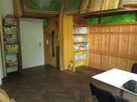 Ein Raum mit einem Holzparkett, vorne rechts steht ein Tisch, in der Zimmerecke ist ein Bücherregal mit einer Spielburg daran, links daneben ist eine weiße Tür und ein weiteres Bücherregal