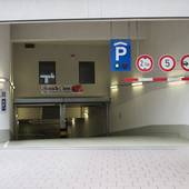 Offene Abfahrt in Tiefgarage. Rechts von Decke abgehängte schwarz-rotes Brett mit 3 Schildern: Einfahrtshöhe 2,1 m, 5 km/h, Anhänger verboten