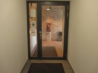 Eine gläserne Tür mit einem dunklem Rahmen. Links neben der Tür ist eine schmale Glasscheibe in der gleichen Höhe.