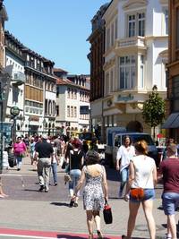 Ausschnitt der Hauptstraße gleich am Anfang beim Bismarckplatz, rechts und links Gebäude mit Läden Hotel usw., etliche Passanten sind unterwegs 
