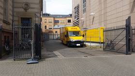 Einfahrt links von Postgebäude, rechts Packstation und DHL-Fahrzeug