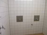 weiß gekachelter Raum mit zwei Duschplätzen