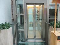 Aufzug mit Glaswänden, auf der Glastür sieht man Zeichen zur Toiletten unten