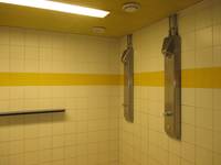 gekachelter Raum mit einem gelben Streifen und zwei Duschplätzen