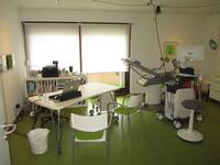 Beratungstisch mit 2 Stühlen für Patient*innen, Behandlungsstuhl und medizinische Geräte vorhanden