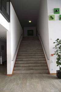 Treppe mit Handläufen führt aufwärts, links und rechts davon Wand