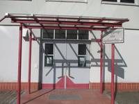 Zweiflügelige Tür mit Glasvordach auf 4 roten Metallsäulen