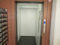 Ein offenstehender Aufzug, Innenkabine hell mit dunklem Boden