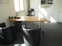 Ein Raum mit einem Schreibtisch mit Stuhl und zwei Sesseln davor