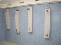 an einer blau gekachelten Wand vier Duschplätze; Duschköpfe in verschiedenen Höhen angebracht