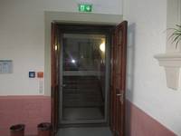 einflügelige geschlossene Glastür, davor eine geöffnete zweiflügelige hölzerne Tür