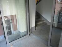 Eine offenstehende Glastür, nach der Tür ist eine aufwärts führende Treppe