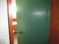  leicht geöffnete grüne Tür in brauner Wand