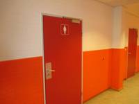 rote Tür in Flur, unterer Teil der Wände orange gestrichen 