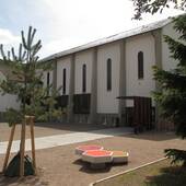 Kirchengebäude mit großem Vorplatz und ebenerdigem Eingangt Schrägdach
