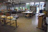 Klassenzimmer mit niedrigen Tischen und Stühlen, breite Fensterfront