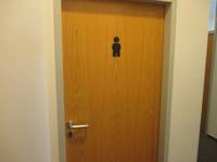 Holztür mit einem schwarzen Toilettenmännchen 