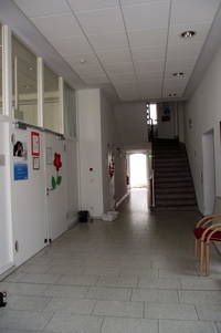 breiter Innenflur nach Eingangstür, links Zugang zu großem Saal, Treppen aufwärts rechts am Ende des Flurs 