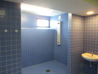 blaugekachelter Bereich mit einem Duschplatz und in Kopfhöhe ein Fenster