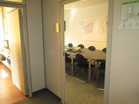 Eine offenstehende Tür, im Raum dahinter ein großer ovaler Besprechungstisch mit Stühlen
