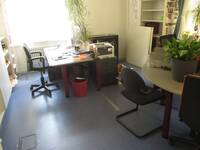 Raum mit einem Schreibtisch mit Stuhl einem kleinen runden Besprechungstisch mit Stühlen