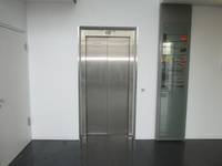 Aufzug mit geschlossener Metalltür und Metallrahmen in weißer Wand