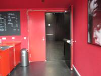 Offen stehende Tür zu TiK/Theatersaal, rechts neben der Bartheke. Die Tür und der Türrahmen sind außen rot und innen schwarz.