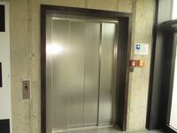 Geschlossene Aufzugstür aus Edelstahl in einer hellen Wand