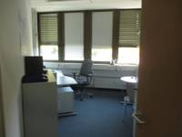 Kleiner möblierter Bürororaum mit Teppichboden und breiter Fensterfront